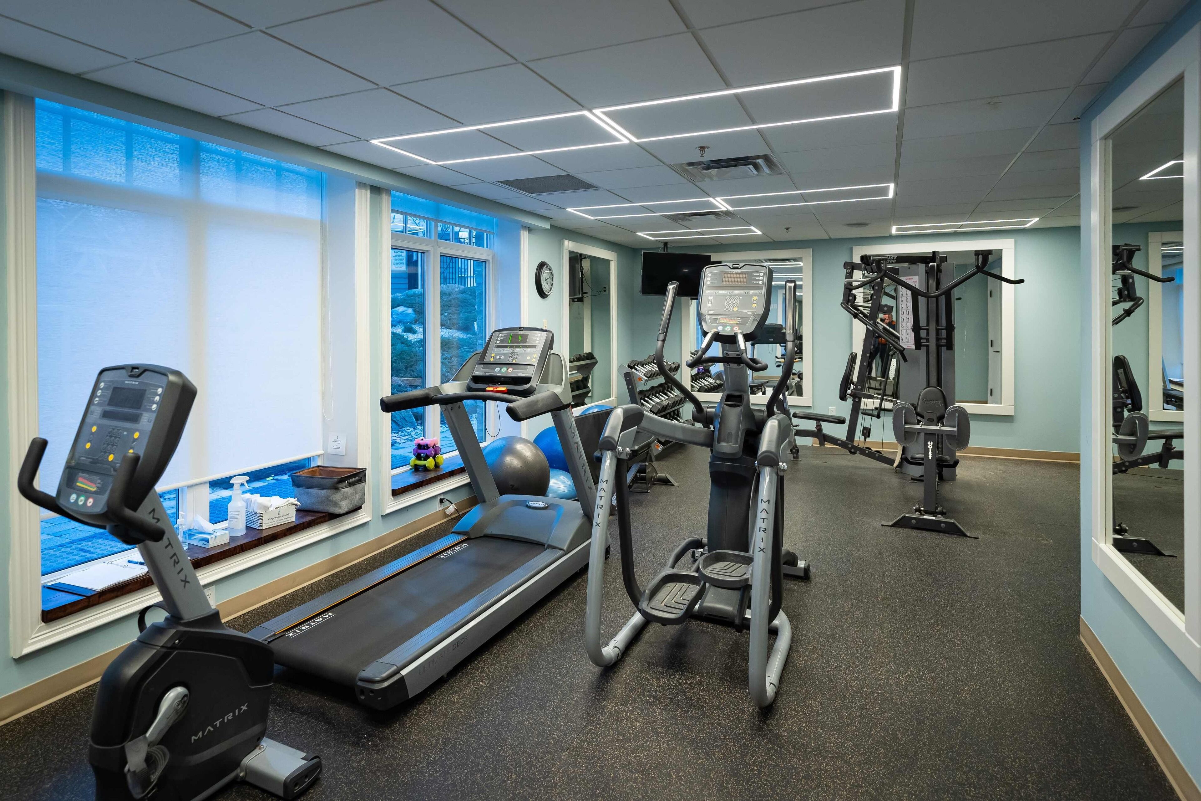 A gym with treadmills, an elliptical, and weight machines.