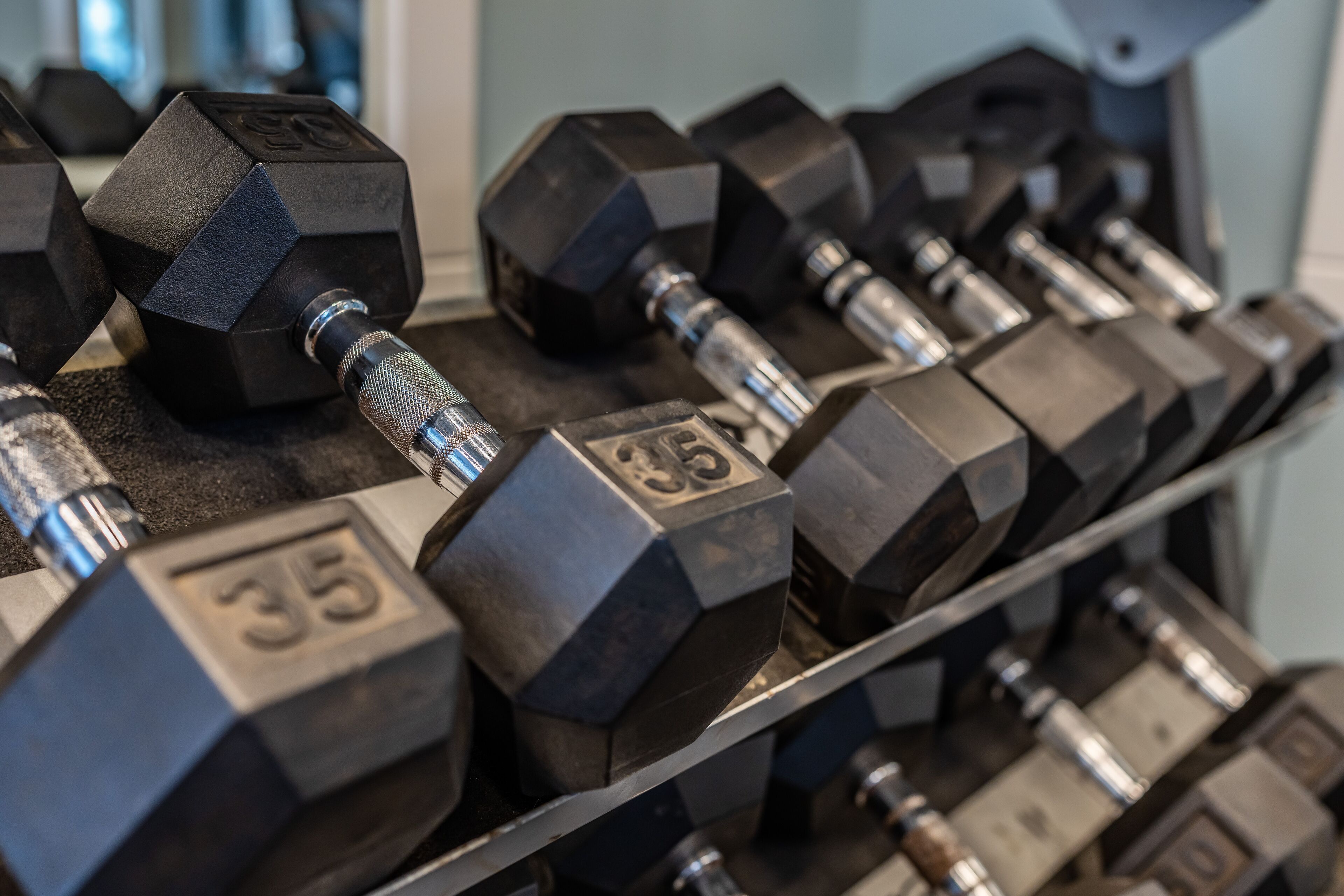 A rack of hexagonal dumbbells with visible weight markings.