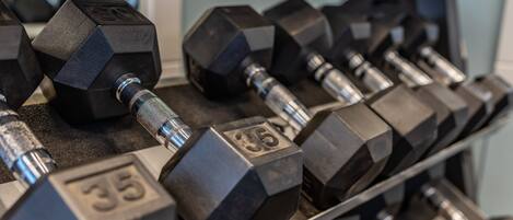 A rack of hexagonal dumbbells with visible weight markings.