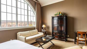 Une chambre d’hôtel avec une grande fenêtre, un canapé, une table basse, un meuble et une chaise.