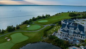 An aerial view of a golf course with a large house and swimming pool. - The Inn at Cobble Beach (Georgian Bluffs)