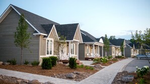 A row of modern single-family homes with a uniform architectural style, featuring pitched roofs and a well-maintained front yard with landscaping. - The Inn at Cobble Beach (Georgian Bluffs)
