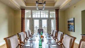 A conference room with a long table, chairs, a chandelier, and large windows. - The Inn at Cobble Beach (Georgian Bluffs)