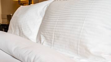 A neatly made bed with white linens and a striped pillow.