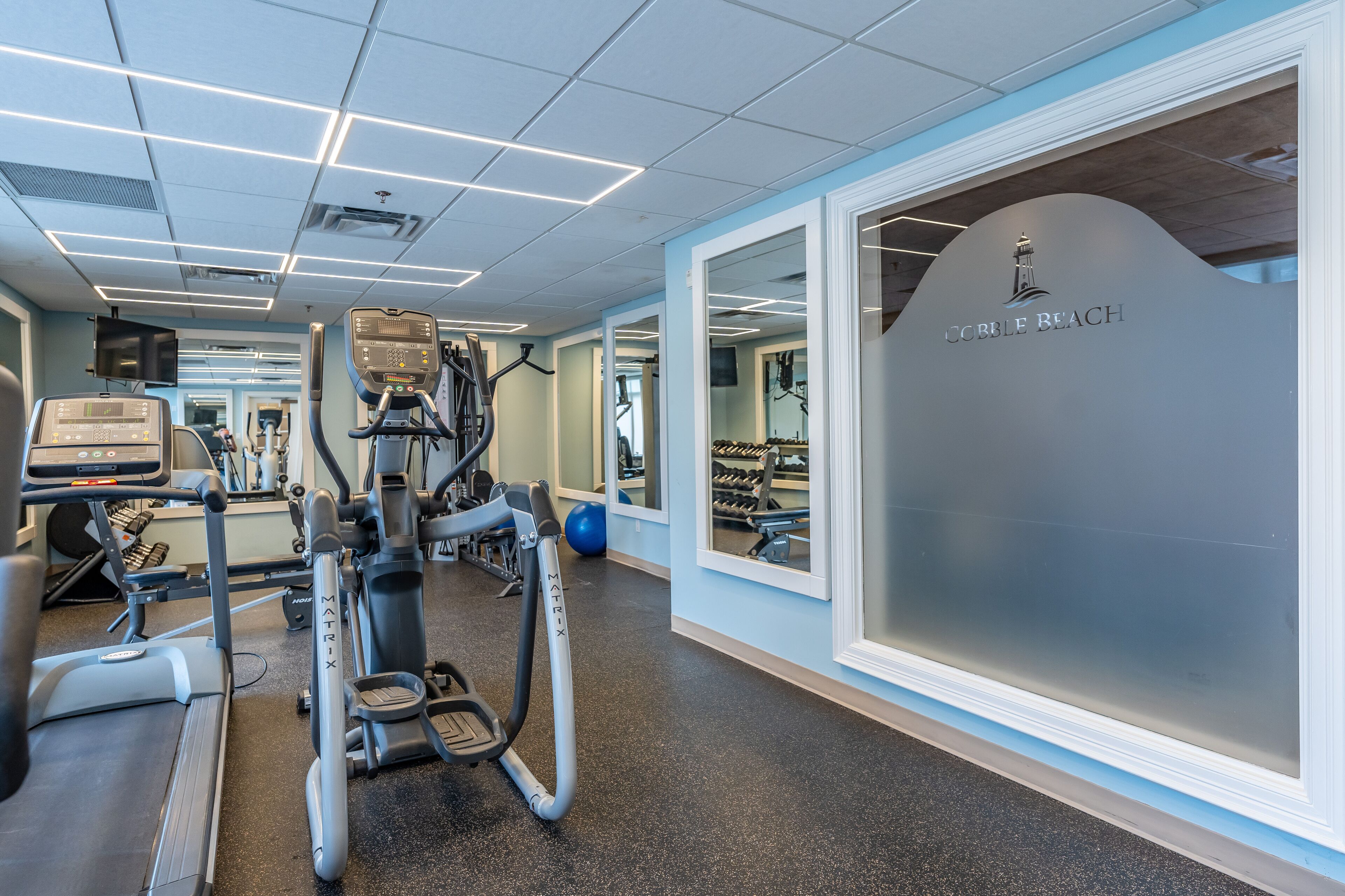 A gym with treadmills, elliptical machines, and exercise balls.