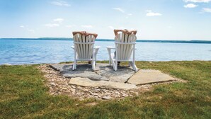 Two Adirondack chairs facing a lake with a clear sky. - The Inn at Cobble Beach (Georgian Bluffs)