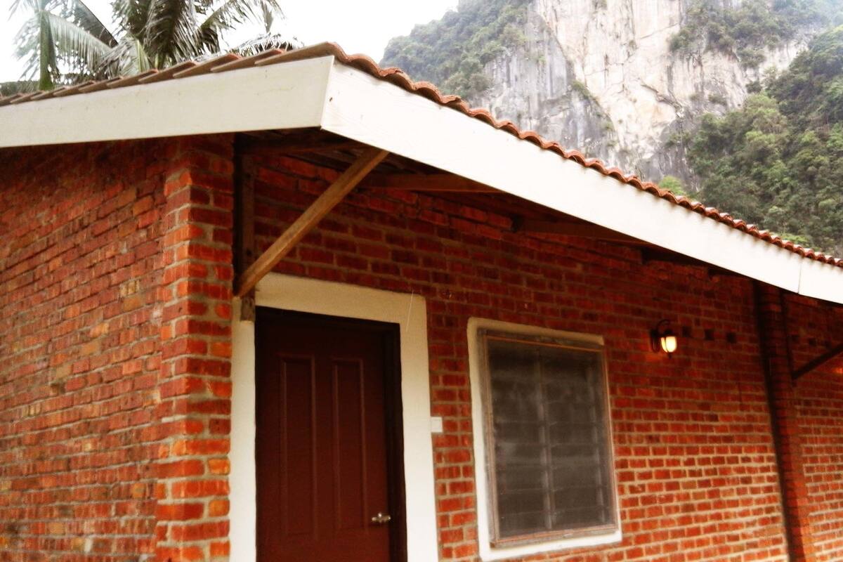 Un edificio de ladrillo con techo blanco, una puerta de madera y una ventana.