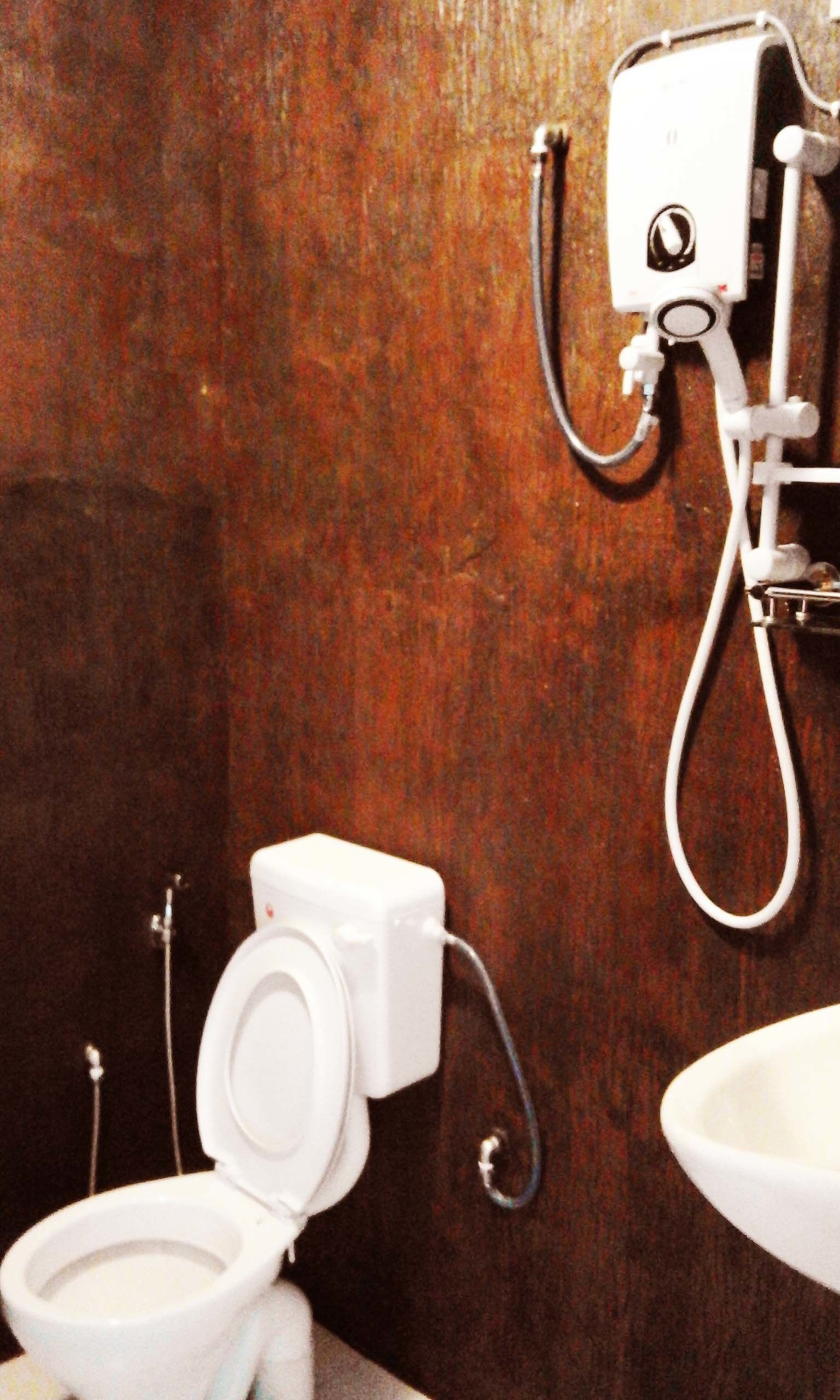Ein Badezimmer mit Toilette, Waschbecken und einer an der Wand befestigten Duschkabine.