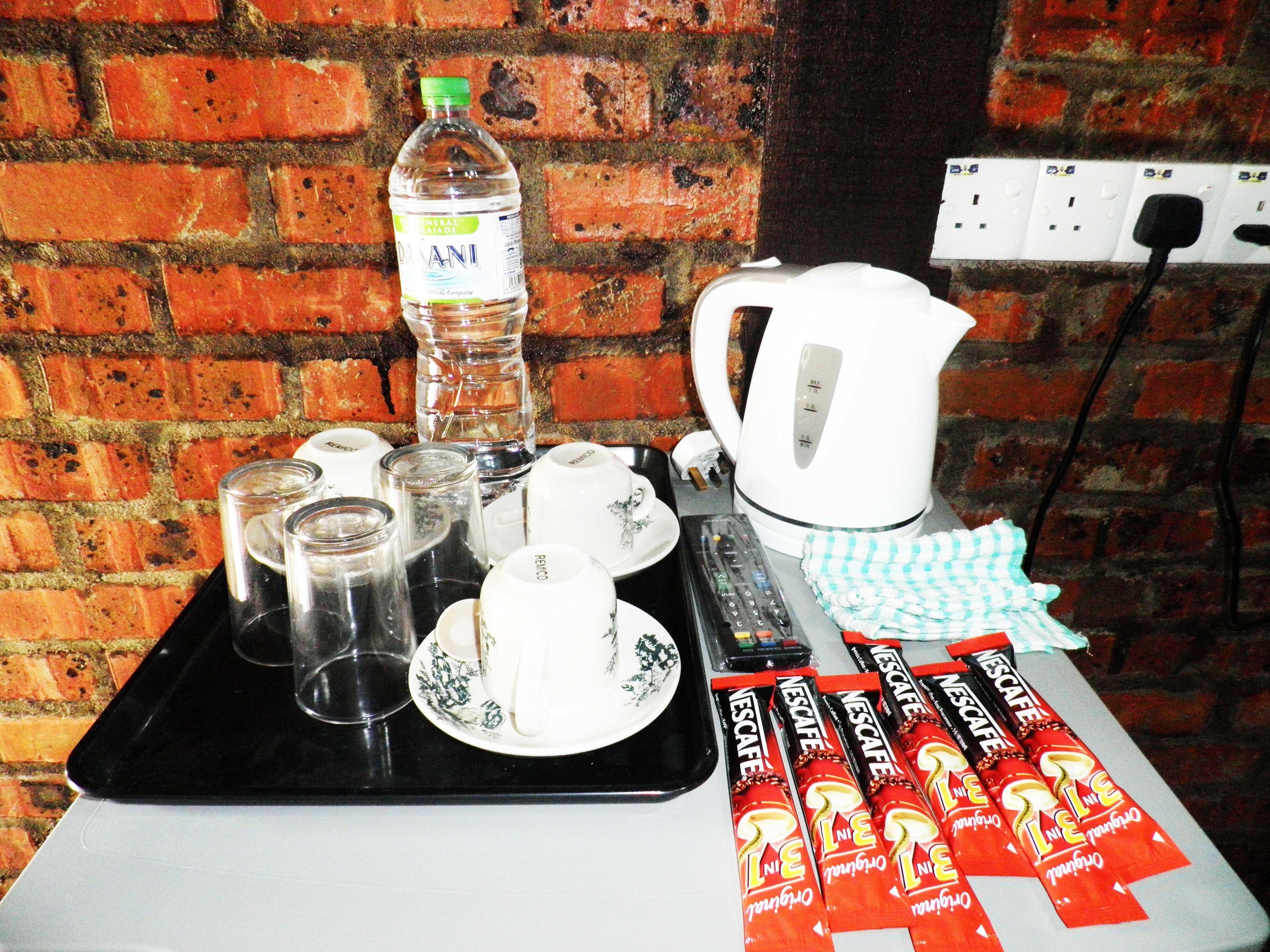 Un tavolo con una bottiglia d'acqua, tazze, un bollitore e confezioni di Nescafe.