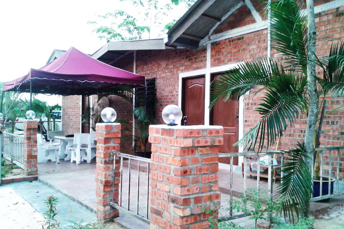 Un edificio de ladrillo con un patio cubierto, una entrada cercada y plantas en macetas.