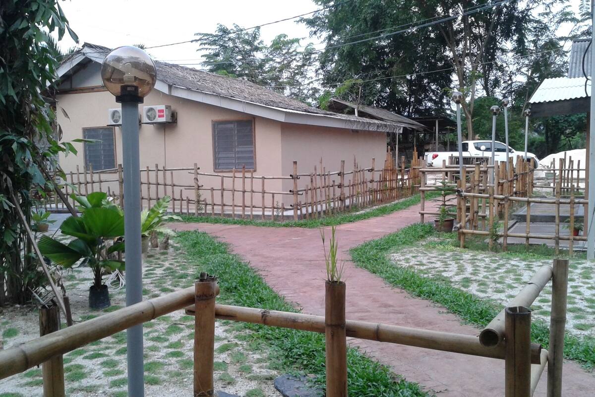 Un edificio con techo de tejas, un área cercada con un sendero de tierra y un vehículo al fondo.