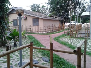 A building with a tiled roof, a fenced area with a dirt path, and a vehicle in the background. - EFM Guest House (Ipoh)