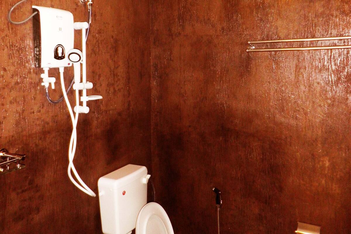Un baño con un inodoro blanco, un bidé de pared y un enchufe visible.