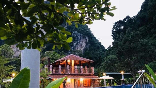 A two-story building with a pool, surrounded by lush greenery and mountains. - EFM Guest House (Ipoh)