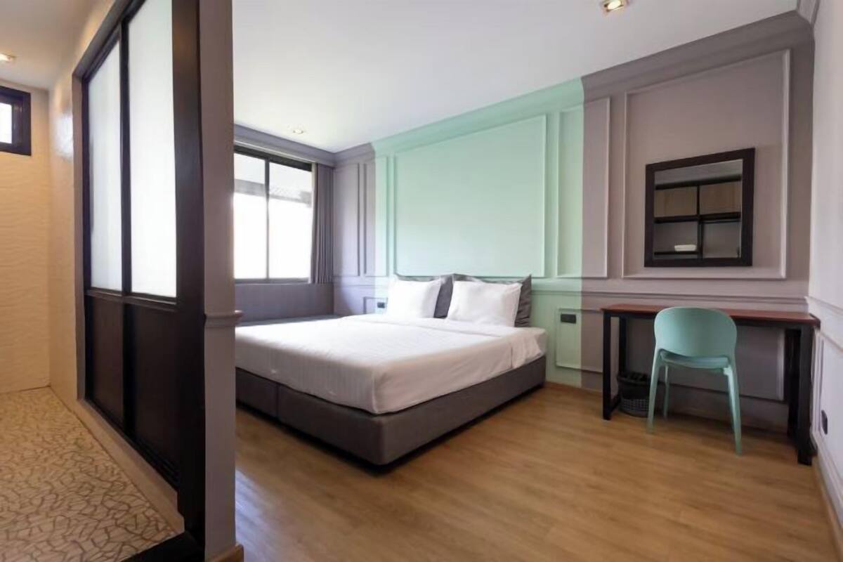 A bedroom with a bed, a desk, and a chair.