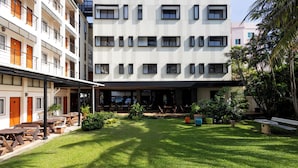 A courtyard with a lawn, outdoor seating, and a building with multiple windows and balconies. - Penpark Place (Bangkok)