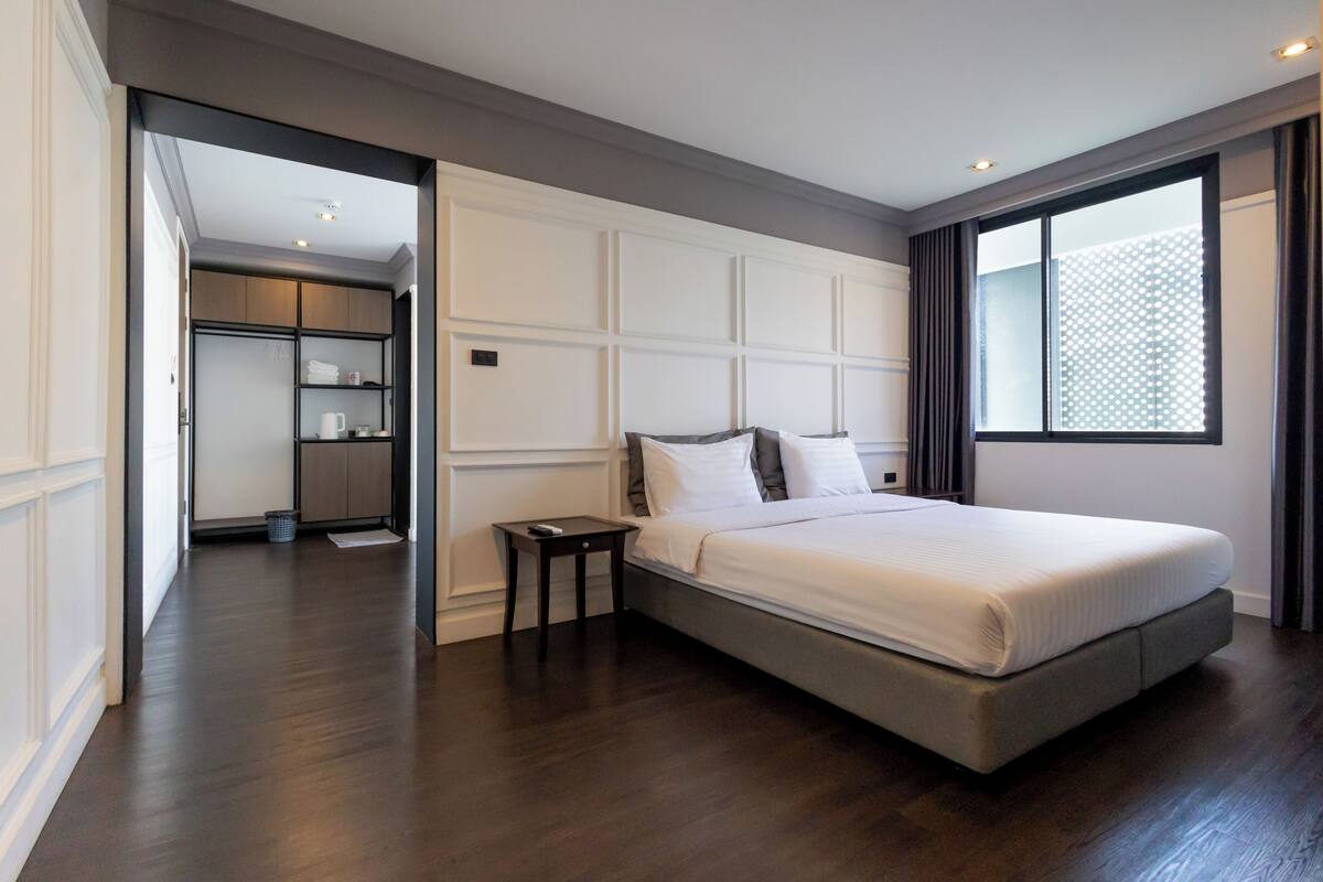 A modern bedroom with a large bed, a nightstand, and a walk-in closet.