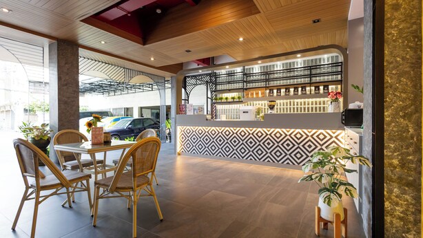 A modern hotel lobby with a reception desk, seating area, and a view of the street. - Penpark Place (Bangkok)