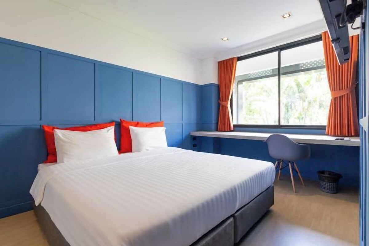 Un dormitorio con cama, escritorio y ventana con cortinas.