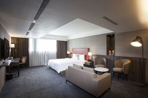 A hotel room with a bed, two armchairs, a desk, a lamp, and a small table. - Citizen Hotel (Taipei)