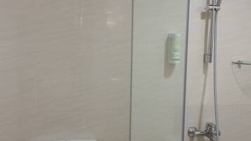 A modern bathroom with a glass-enclosed shower, a toilet, and a control panel.