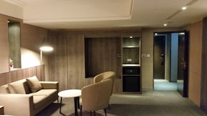 Una habitación de hotel moderna con un sofá, dos sillones, una mesita y estanterías empotradas.