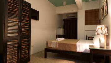 A bedroom with a bed, a wardrobe, a bedside table with a lamp, and a window with blinds.