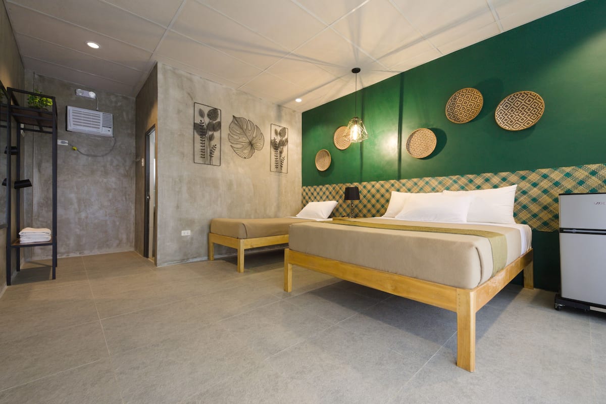 A hotel room with a bed, a bench, a wardrobe, and a small refrigerator.