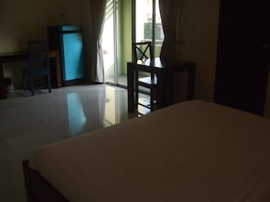 A room with a bed, a desk, a chair, and a small table.