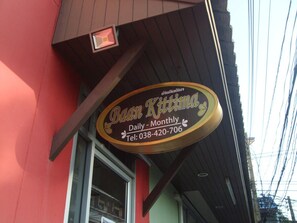 A storefront with a sign that reads "Baan Kittima Daily - Monthly" and a telephone number.