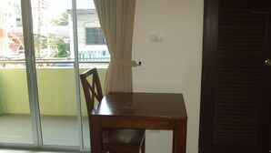 A dining area with a wooden table and chairs, a sliding glass door leading to a balcony, and a dark wooden door. - Baan Kittima (Pattaya)
