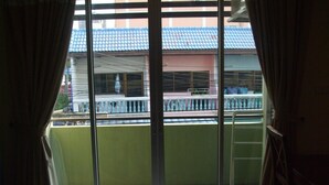 A balcony with a view of a building with a blue roof and a pink wall. - Baan Kittima (Pattaya)