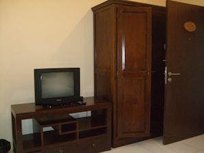 A wooden cabinet with a television on top, a door with a lock, and a small circular plaque on the wall.