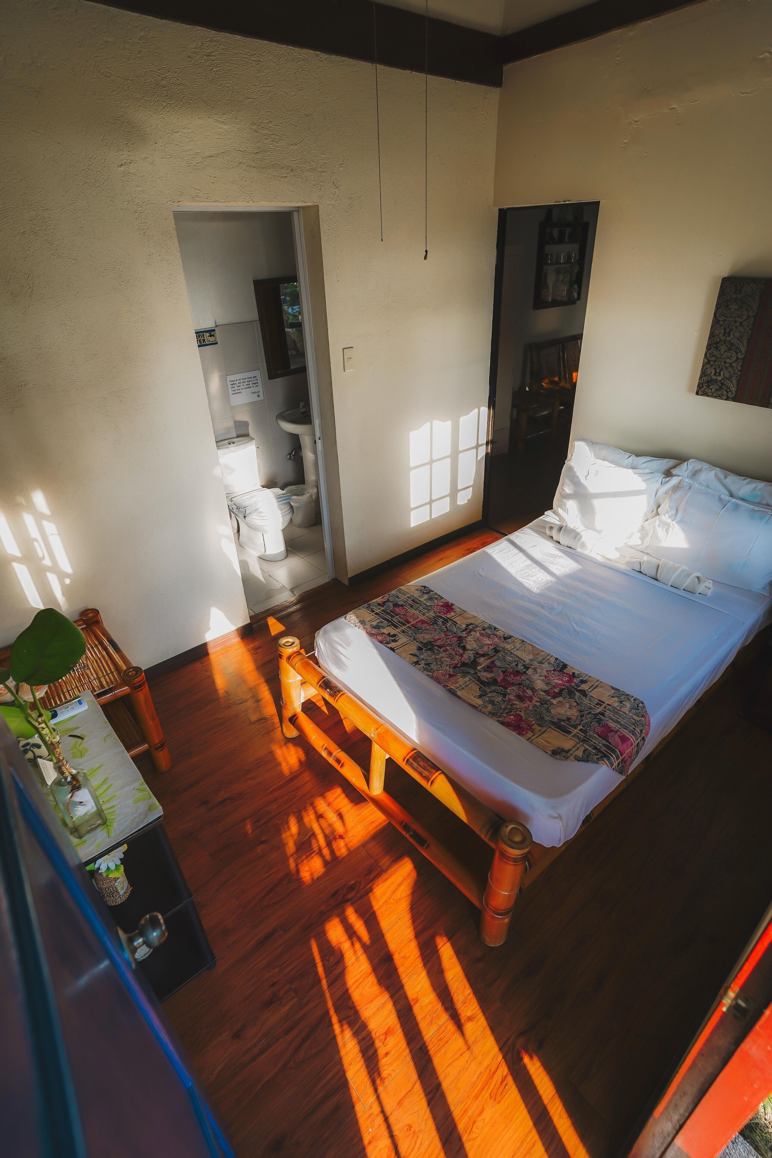Un dormitorio con una cama de madera, una mesita de noche y un ventanal que deja entrar luz natural.