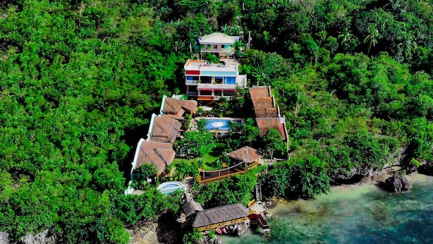 Un resort con varias construcciones rodeado de exuberante vegetación y aguas cristalinas.