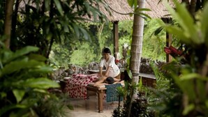 A person receiving a massage in a lush, green outdoor setting with a thatched roof structure. - Chosa Manglar Nature Retreat (Puerto Jiménez)