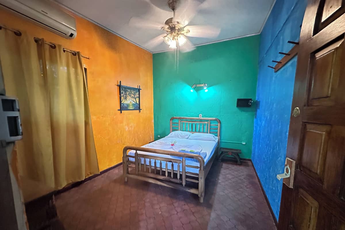 Een slaapkamer met een bed, een plafondventilator en een aan de muur bevestigde airconditioning.