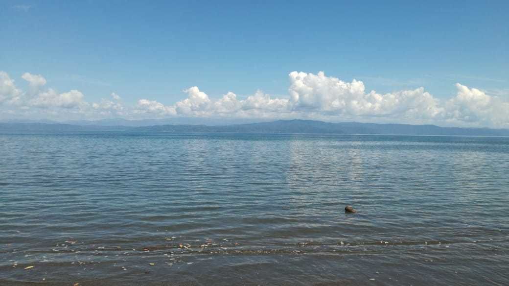 A calm body of water with a distant mountain range under a clear sky.