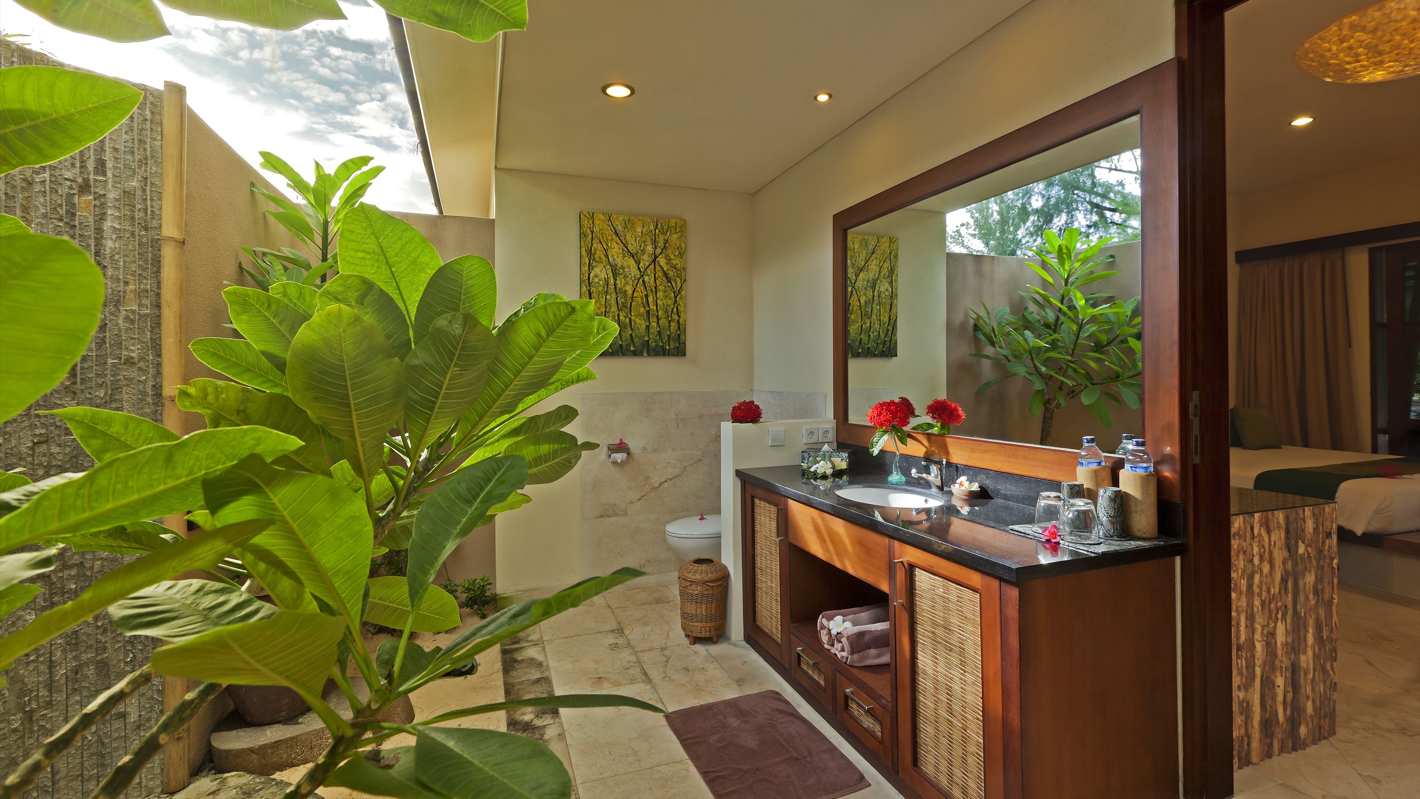 Een moderne badkamer met een grote spiegel, een wastafel en een toilet. Er staan planten en er is een raam voor natuurlijk licht.