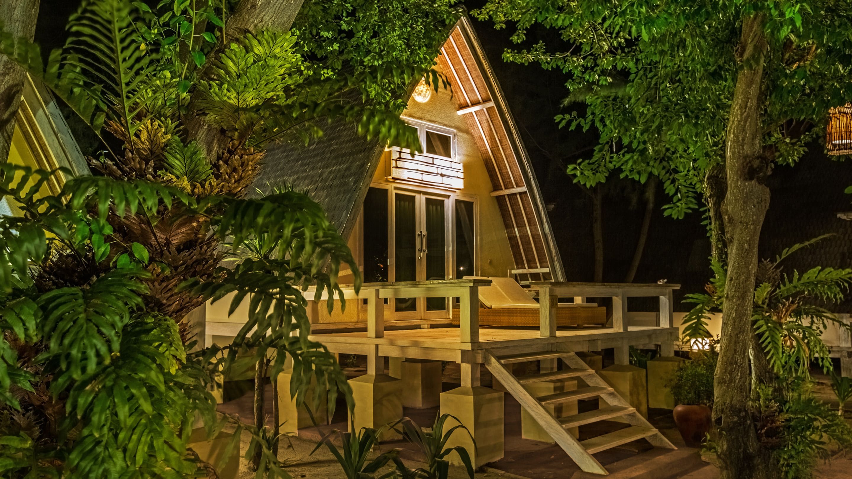 Una casa con techo inclinado, un balcón y una escalera que lleva a la entrada.