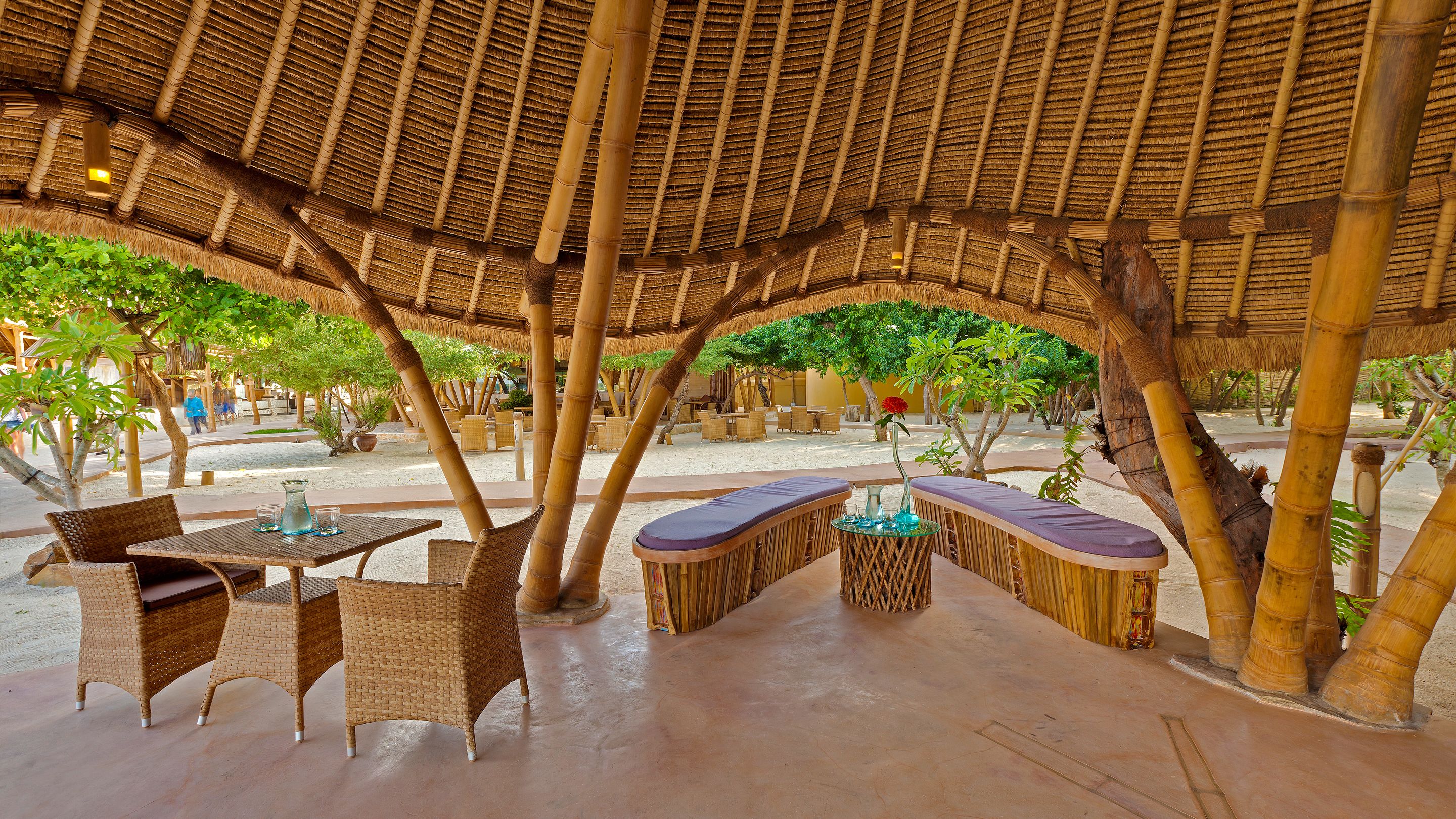 An outdoor seating area with bamboo furniture and a thatched roof.