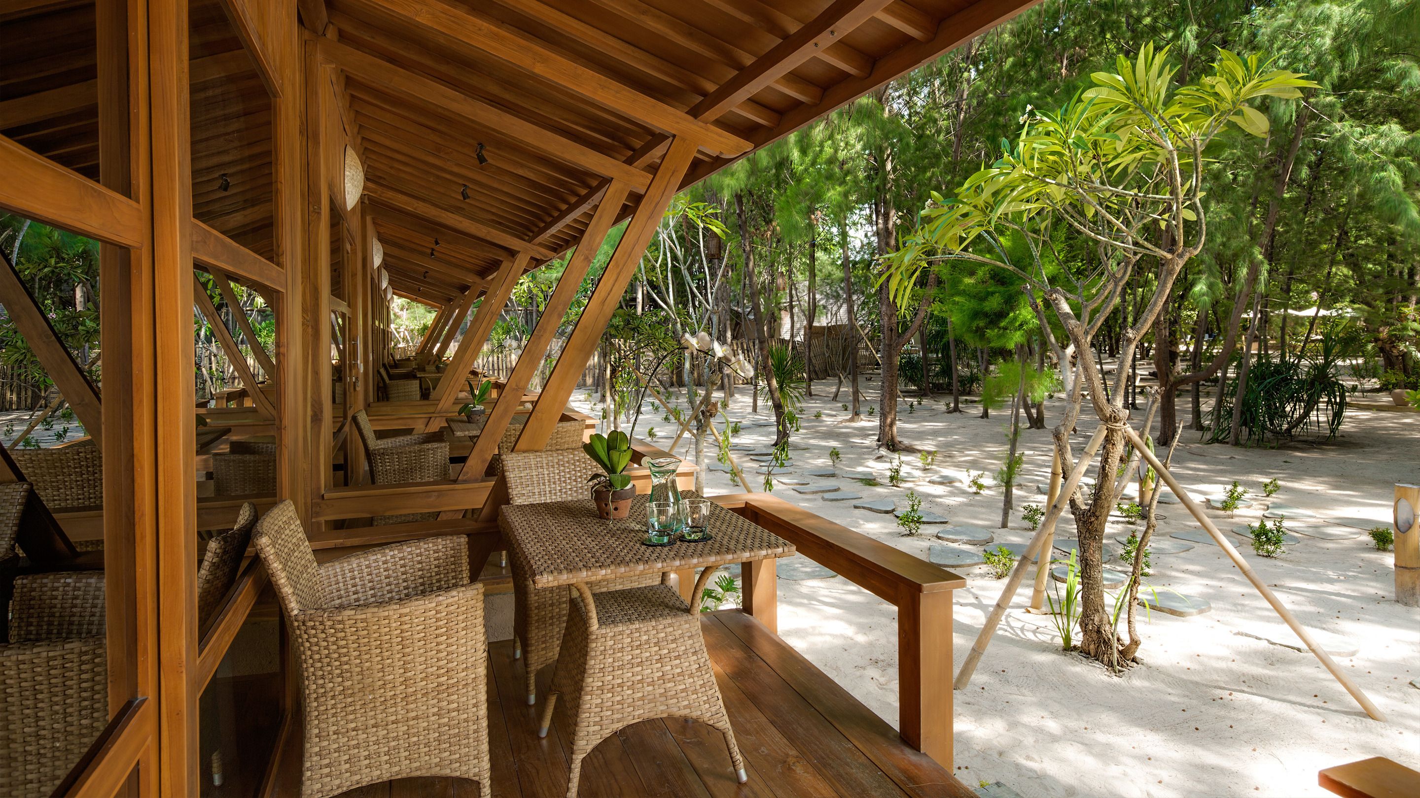 A covered outdoor seating area with wicker furniture and a wooden pergola.