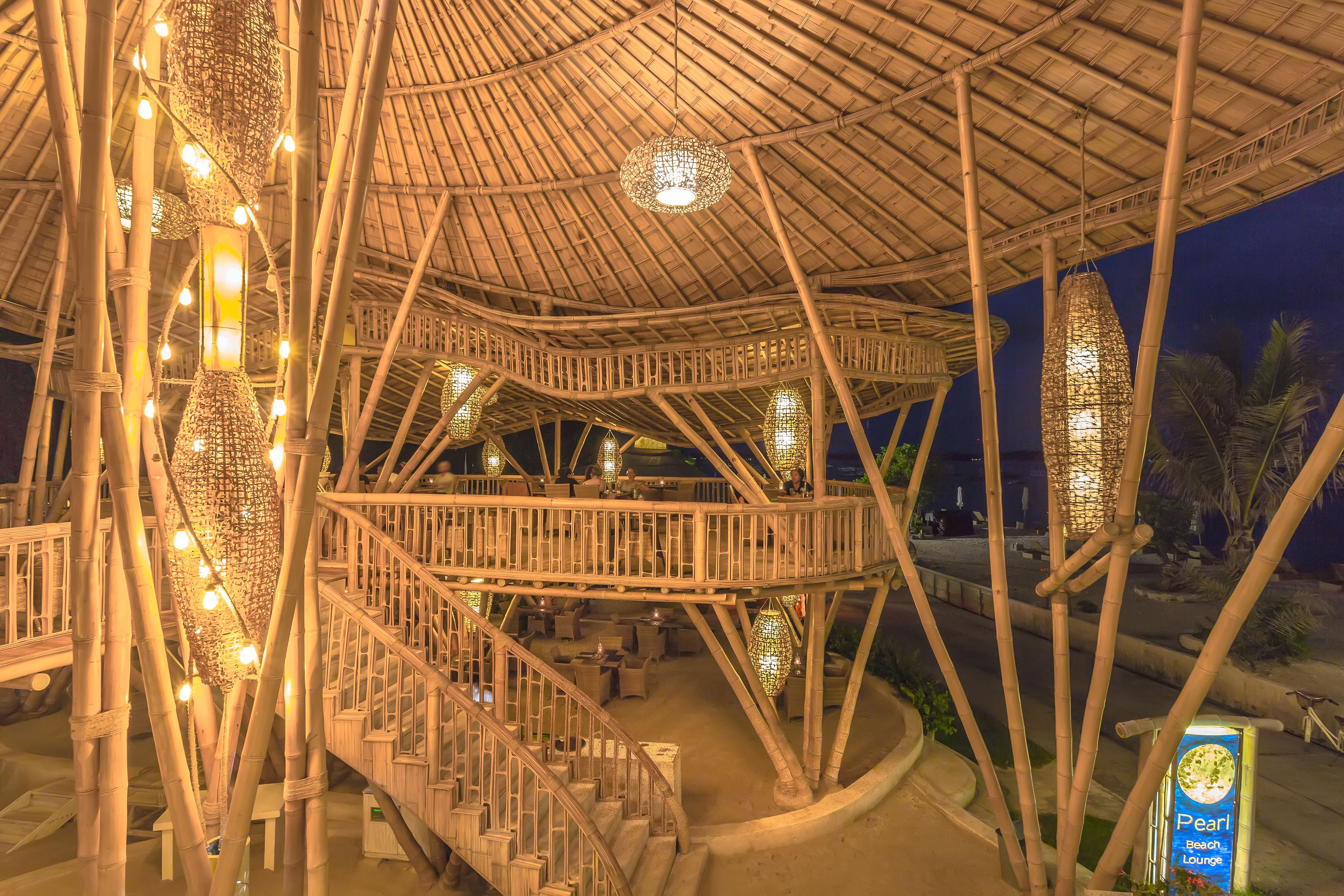 A multi-level bamboo structure with outdoor seating and a staircase.