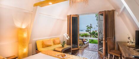 A bedroom with a bed, a sofa, a desk, and a balcony with a view.