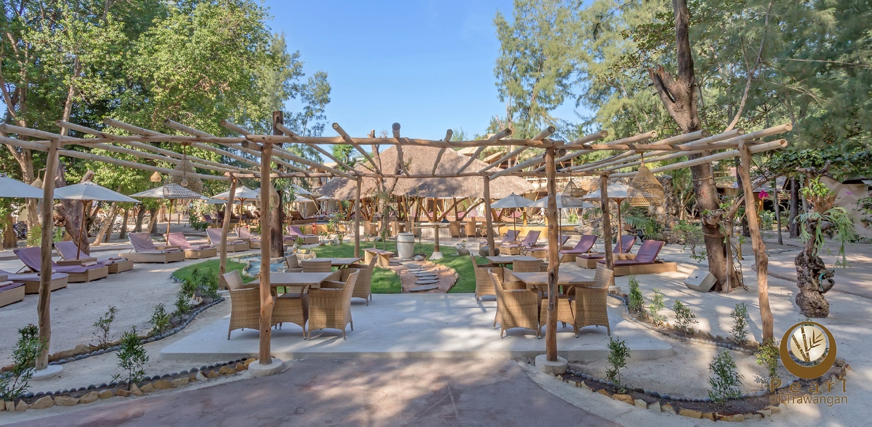Ein ruhiger Außenbereich mit reetgedeckten Sonnenschirmen, Korbmöbeln und einer Holzpergola.