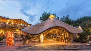 Un resort con una estructura de techo de paja única, un área de recepción y un letrero que indica que es el 'Pearl of Travanian Resort'.