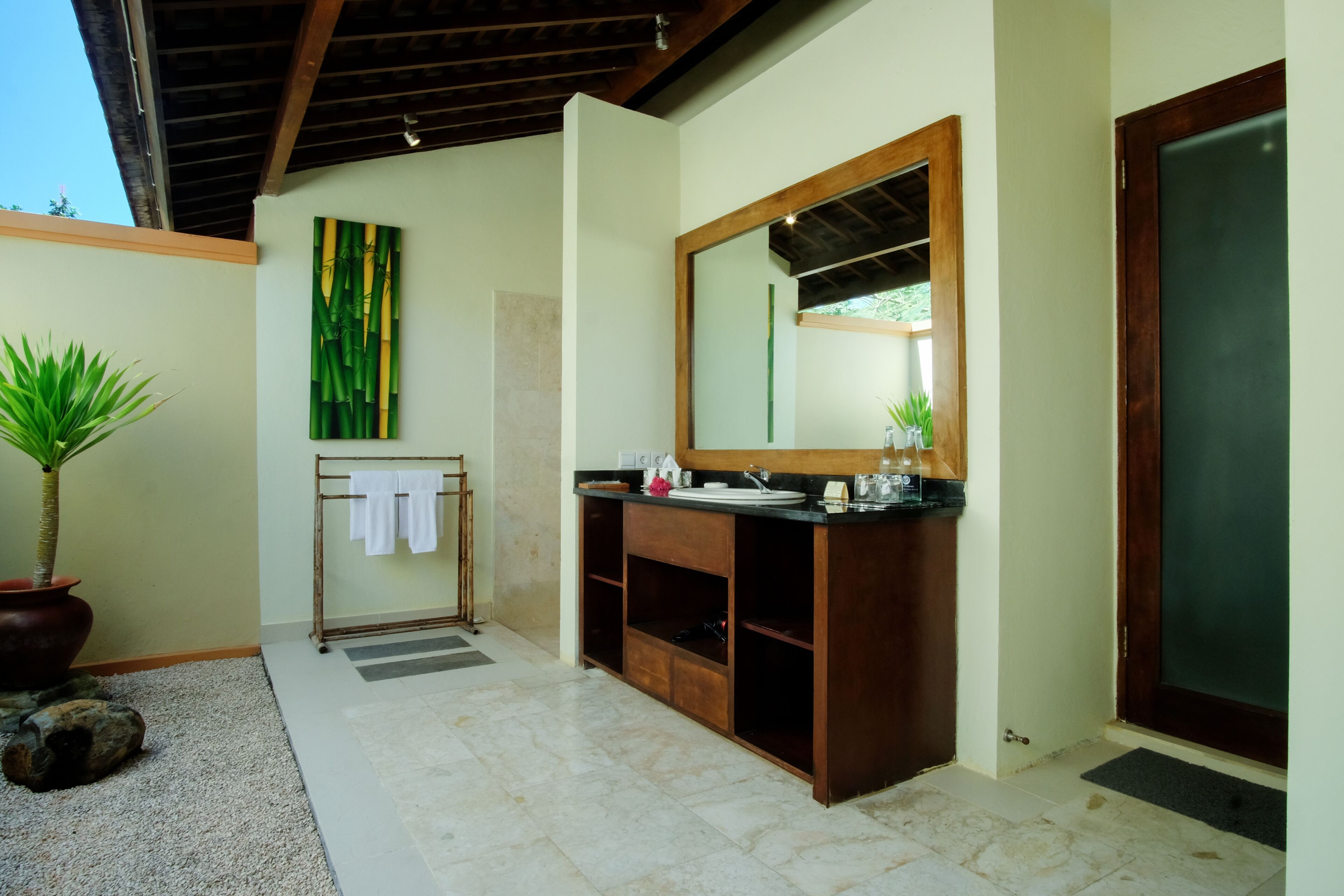 A bathroom with a wooden vanity, a large mirror, and a towel rack.