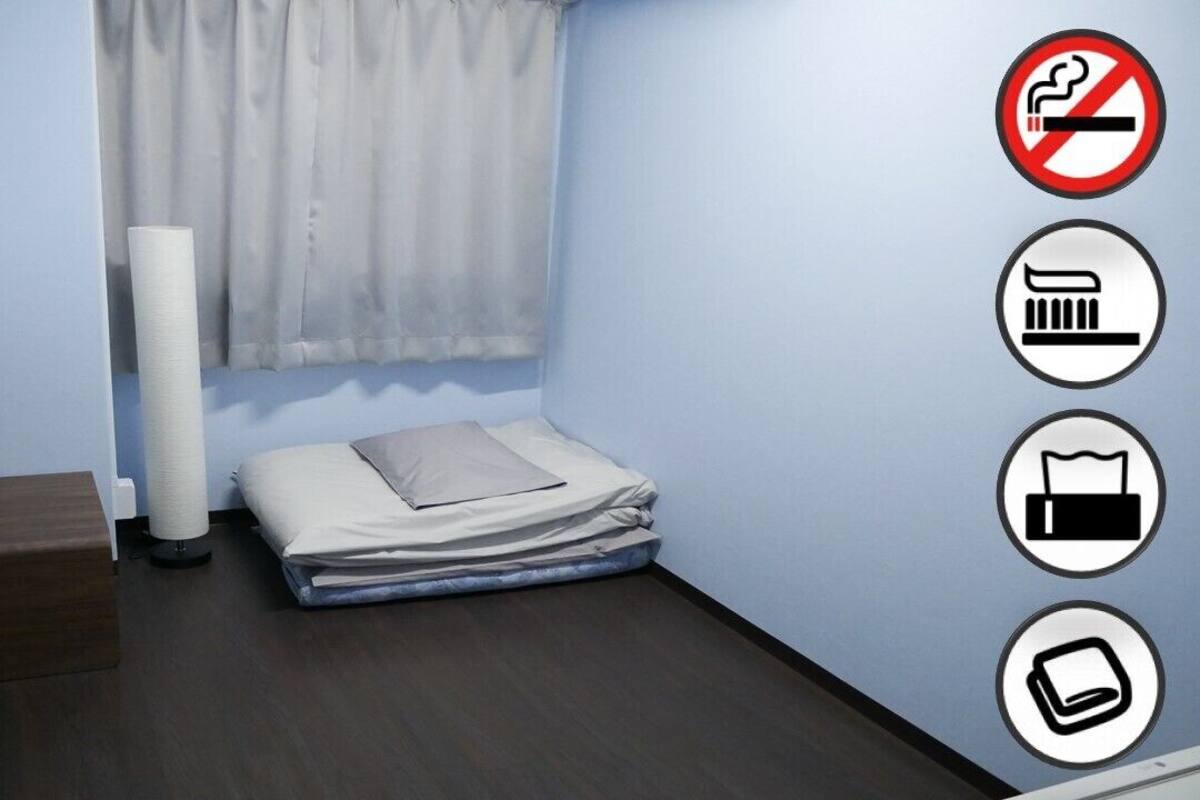 A small room with a bed, a wooden chest, and a window with curtains.