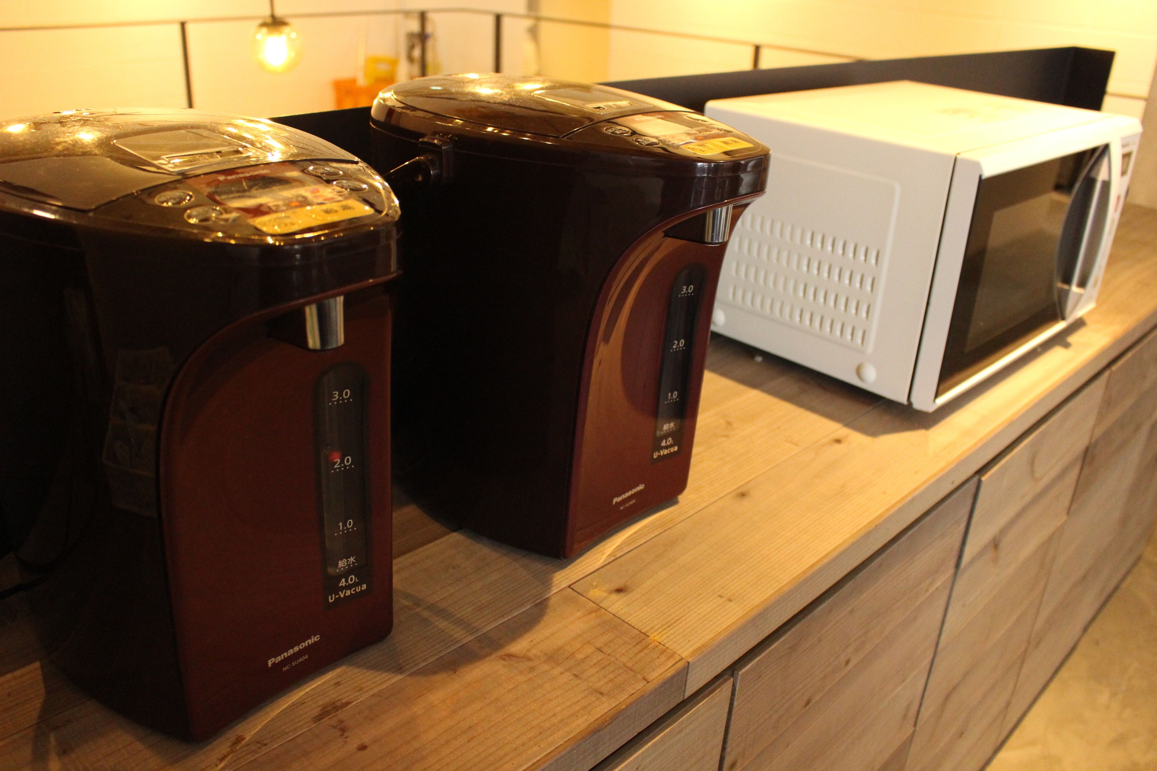A kitchen counter with a microwave and two coffee makers.