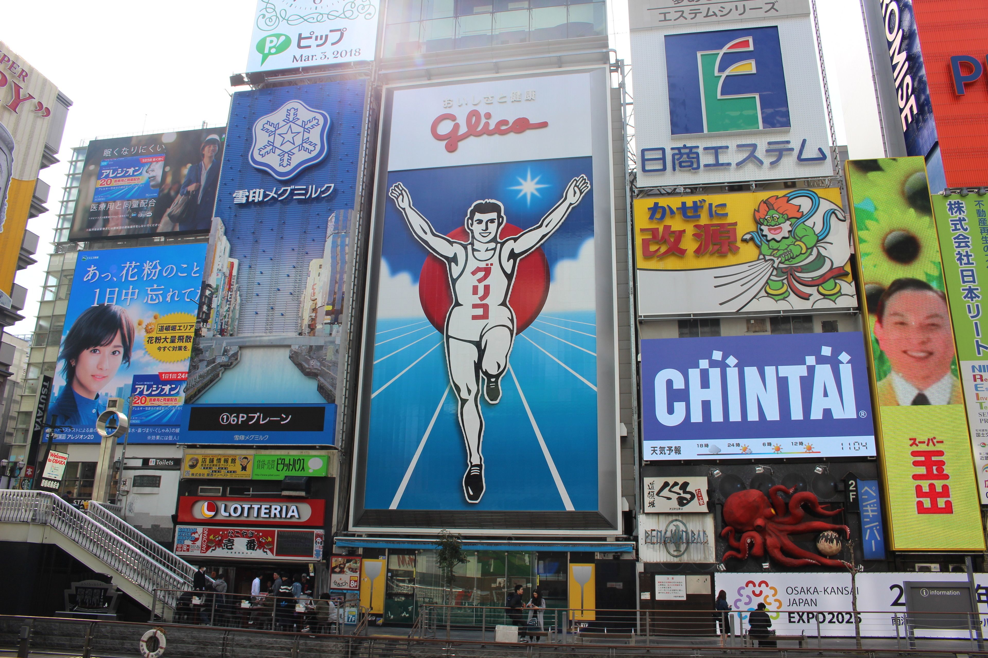 A busy urban street with various commercial billboards and signs.
